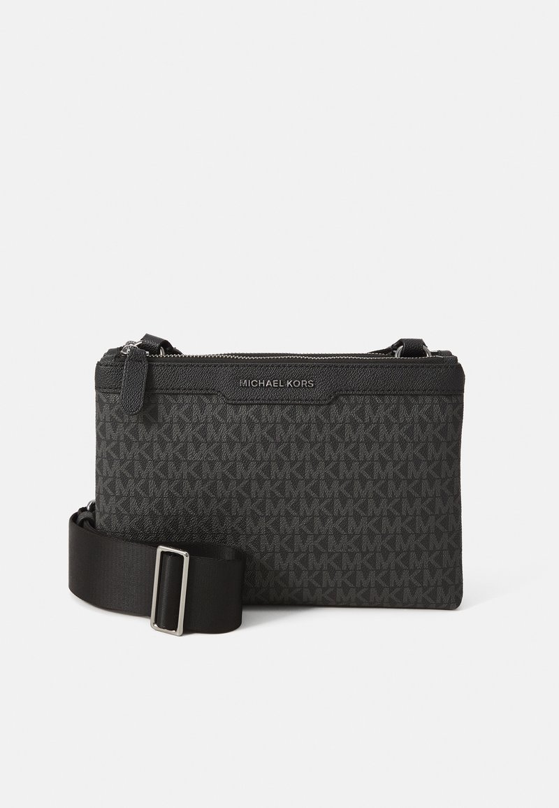 Black crossbody bag made of textured material with repeating logo pattern, features a zip closure and adjustable strap with a metal buckle.