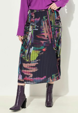Plisséd midi rok met een donkere basis en kleurrijke abstracte patronen, aangevuld met strakke paarse enkellaarzen met blokhakken.