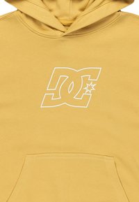 Sudadera con capucha amarilla, hecha de tejido suave, que presenta un gran logo blanco de DC en el pecho y un bolsillo frontal. Diseño simple sin patrones.