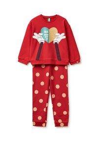 Sudadera roja con manos impresas sosteniendo un corazón turquesa y dorado, combinada con pantalones rojos con grandes lunares beige.