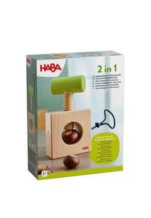 Holzkastanienbohrer und Nussknacker-Spielzeug mit grünem Griff, Kastanien darin und herum, Verpackung zeigt Produktdetails.