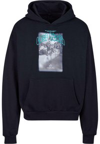 Melnā kapucē ar priekšējo kabatu, ar grafisku druku, kas attēlo izplūdušu ainavu, un zilu tekstu, kas saka "PĒDĒJAIS JAUNIEŠU" un "SEKOJAM ŠAI SAPNIM."