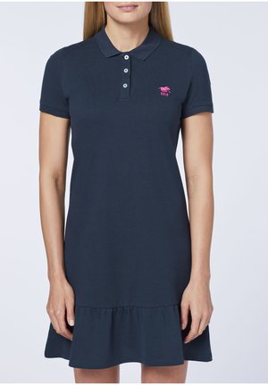 Marineblaues Polo-Kleid mit kurzen Ärmeln, geripptem Stoff, Knopfleiste und schwingendem Rüschensaum. Mit einem pinkfarbenen, gestickten Logo auf der Brust.