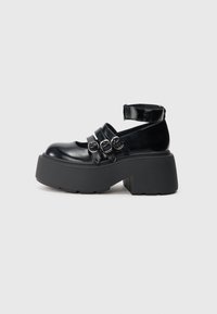 Zwarte platform schoenen van glanzend materiaal, met drie verstelbare riemen met zilveren gespen en een dikke rubberen zool.