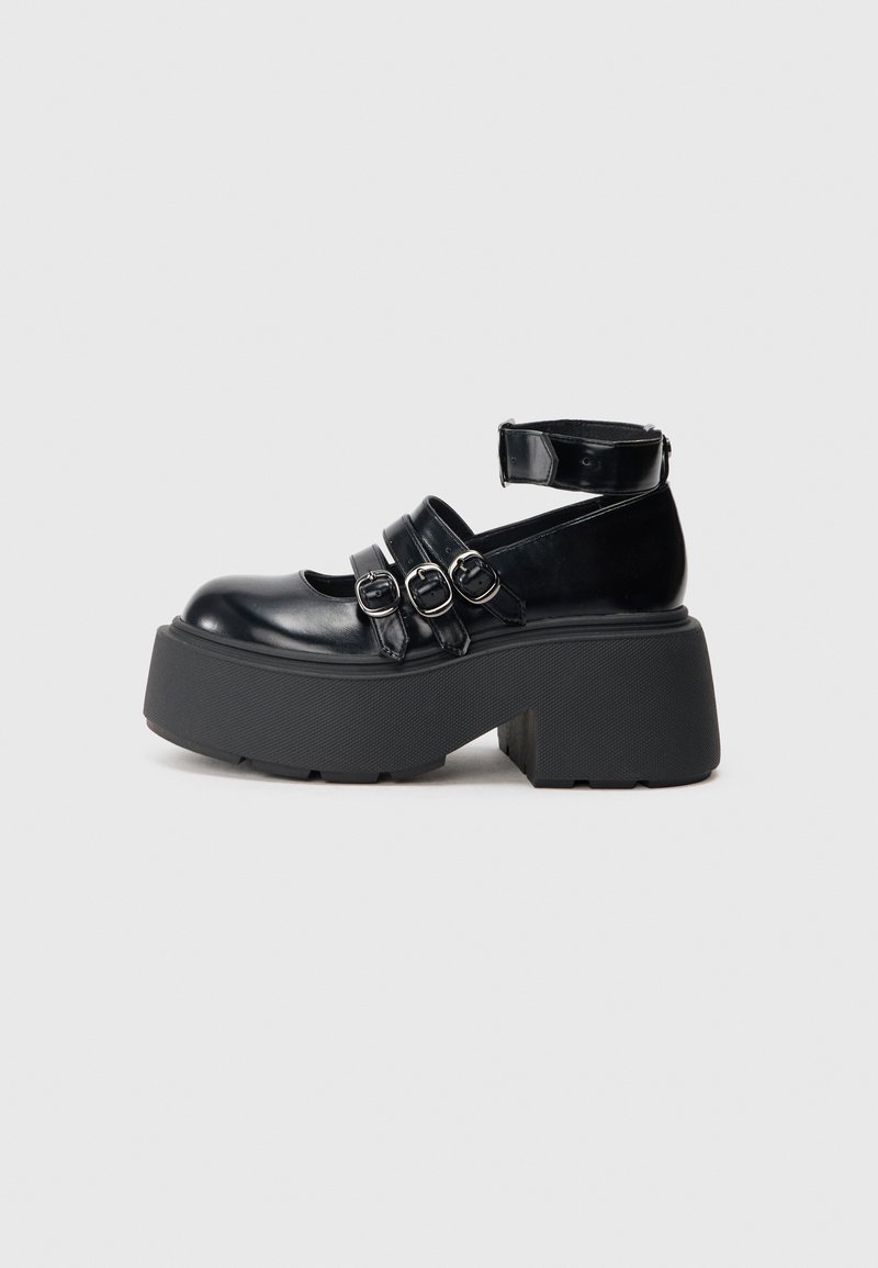 Zwarte platform schoenen van glanzend materiaal, met drie verstelbare riemen met zilveren gespen en een dikke rubberen zool.