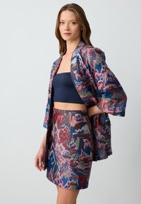 Mehrfarbiger Satin-Kimono mit passendem Rock. Verfügt über abstrakte Muster in Blau-, Pink-, Grün- und Rottönen. Glatte Textur.