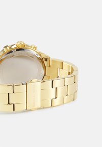Orologio in acciaio inossidabile dorato con bracciale a maglie lisce, cassa rotonda e corona testurizzata. Include una finitura lucida e un logo inciso sulla chiusura.