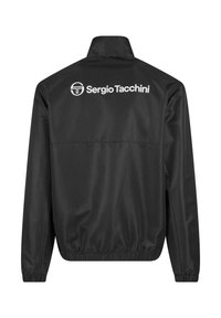 Črna jakna iz gladkega blaga, z vzdevkom in elastiko na koncih rokavov. Bel logotip "Sergio Tacchini" na hrbtni strani.