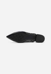 Chaussures noires à bout pointu avec une semelle texturée, un design à enfiler et un imprimé floral discret sur le dessus. Fini lisse et talon bas.