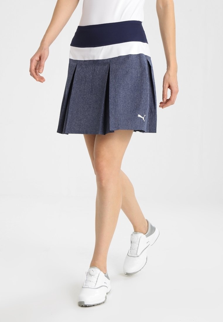 Navy pleated golf skirt dengan waistband lebar yang kontras. Terbuat dari kain tekstur, dilengkapi dengan logo kecil berwarna putih di bagian hem.