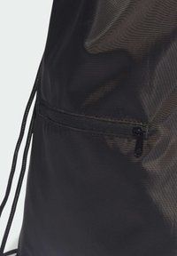 Bolsa de cuerda negra con superficie de nylon texturizada y un pequeño bolsillo con cremallera negra. Diseño simple y funcional.