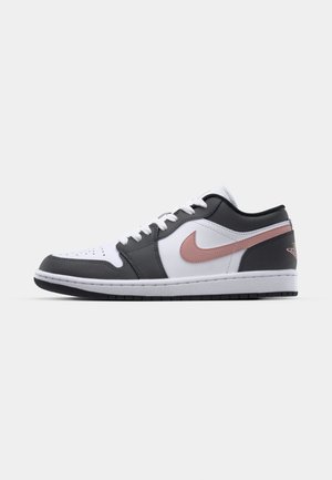Lage sneaker met een witte leren neus, zwarte leren zijpanelen en een metallic roze swoosh. Rubberen zool met een gestructureerde grip.