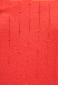 Tissu tricoté rouge avec un motif vertical subtil de groupes de mailles en relief, espacés uniformément sur toute la surface.