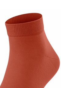 Chaussette en coton orange à la cheville avec une bande supérieure côtelée et une texture lisse, présentant une forme ajustée qui ép épouser la cheville.