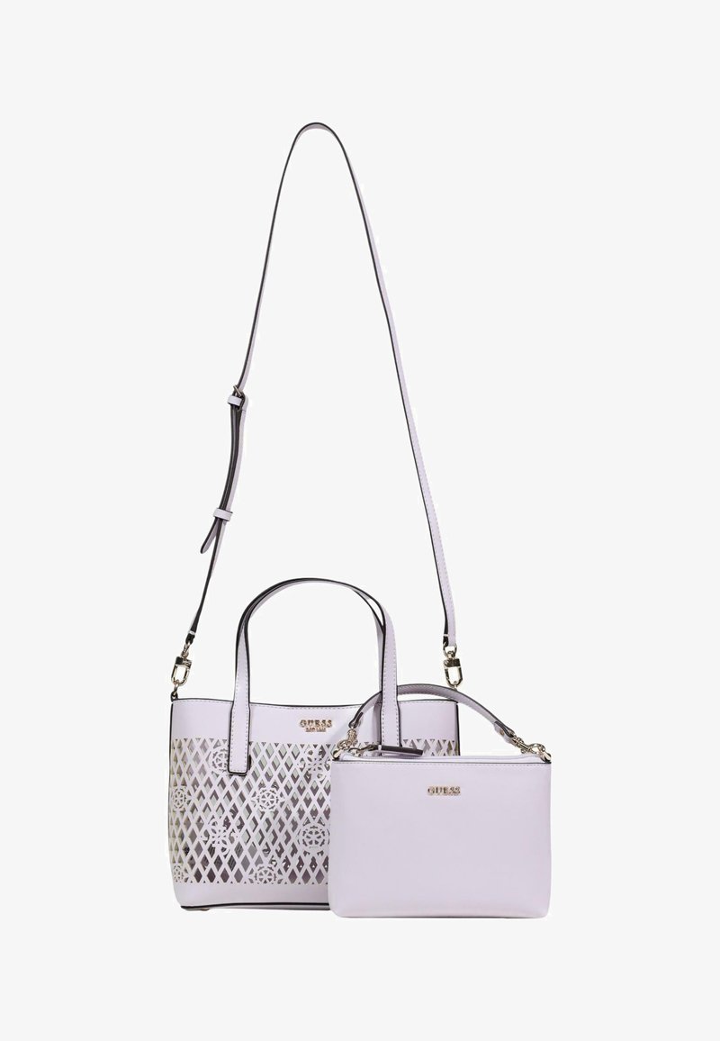 Sac fourre-tout blanc Guess avec un motif floral en treillis en découpe, accompagné d'une pochette blanche plus petite amovible à bandoulière, toutes deux ornées de logos dorés.