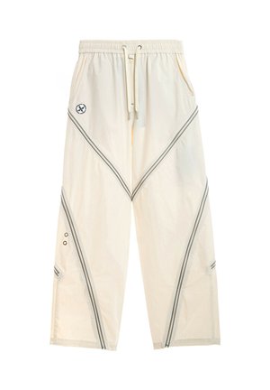 Pantalones de corte ancho color blanco roto con cintura elástica, cordón frontal, bolsillos laterales, rayas diagonales negras y pequeño logo circular en el muslo izquierdo.