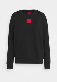 Sudadera negra de cuello redondo de algodón, con una parche rectangular rojo con el logo "HUGO" en el pecho. Puños y dobladillo acanalados.