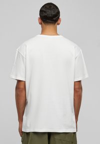Tricou alb din bumbac, cu o croială lejeră, mâneci scurte, gât rotund și o textură netedă. Fără branding sau modele vizibile.