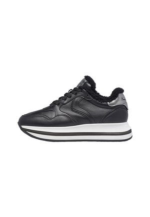 Black sneaker with a leather upper, plush black lining, silver accent on the heel, and a white midsole with black stripes for traction.
