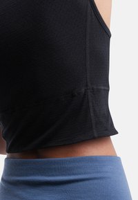 Mustat tekstuurilla varustetut lyhythihaiset crop-topit, joiden leveät kainalot yhdistyvät vaaleansinisiin korkea vyötäröisiin alaosiin, joissa on erityiset saumadetails.