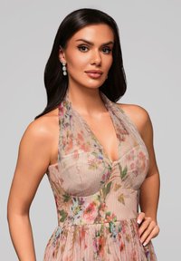 Kwiatowa sukienka na halter z plisowanym teksturem, w odcieniach pastelowych i dopasowanym topie. Dodatki to błyszczące kolczyki.