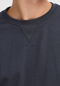 Marineblaue Rundhals-Sweatshirt mit geripptem Kragen, strukturiertem Nähen an der Kragennaht und einem glatten Baumwollstoff-Finish.