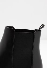 Stivale alla caviglia nero con esterno in pelle liscia, pannello elastico e linguetta sul retro per una facile calzata.