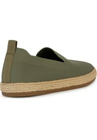 Zapatillas verdes tipo slip-on hechas de tela texturizada, con una suela de cuerda de yute y una base de goma para mayor agarre, con un diseño de corte bajo y lengüeta en el talón.
