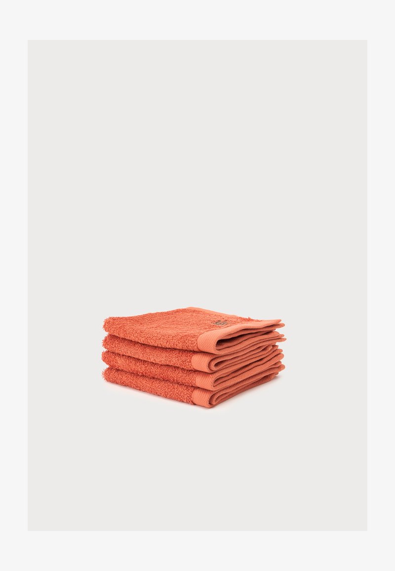 Pile de trois serviettes pliées de couleur corail avec un tissu texturé sur un fond gris clair.