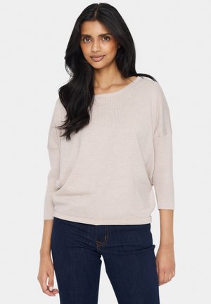 Maglione beige chiaro con una vestibilità rilassata, design a scollo a barca e maniche a tre quarti. Tessuto a coste alle maniche e all'orlo. Indossato con jeans scuri.