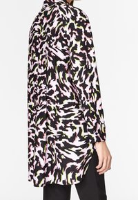 Pitkähihainen paita värikkäällä eläinkuosilla, jossa on mustaa, vaaleanpunaista ja vihreää. Sileä kangas, rento malli ja sivuhalkiot.