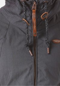 Šedá bunda se zipem na přední straně, nastavitelnými hnědými táhly a černými šňůrami pletenými do copu. Má jemnou texturu a značkovou nášivku na boku.