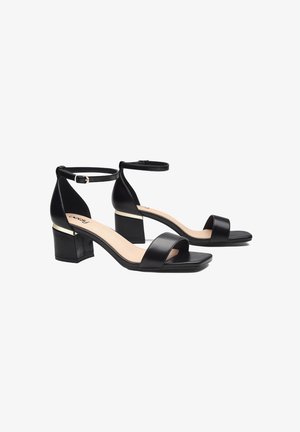 Zwarte hoge hak sandalen met een vierkante neus, enkelband en blokhak met een metallic accent. Glad leren afwerking, open ontwerp.