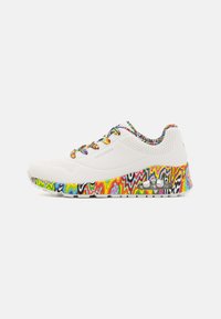 Zapatilla blanca con una parte superior texturizada, que presenta una suela con un patrón de zigzag colorido y cordones multicolores. Logotipo de la marca visible en el lateral.