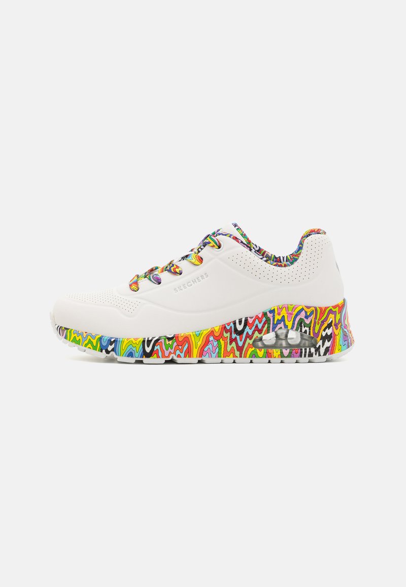 Zapatilla blanca con una parte superior texturizada, que presenta una suela con un patrón de zigzag colorido y cordones multicolores. Logotipo de la marca visible en el lateral.