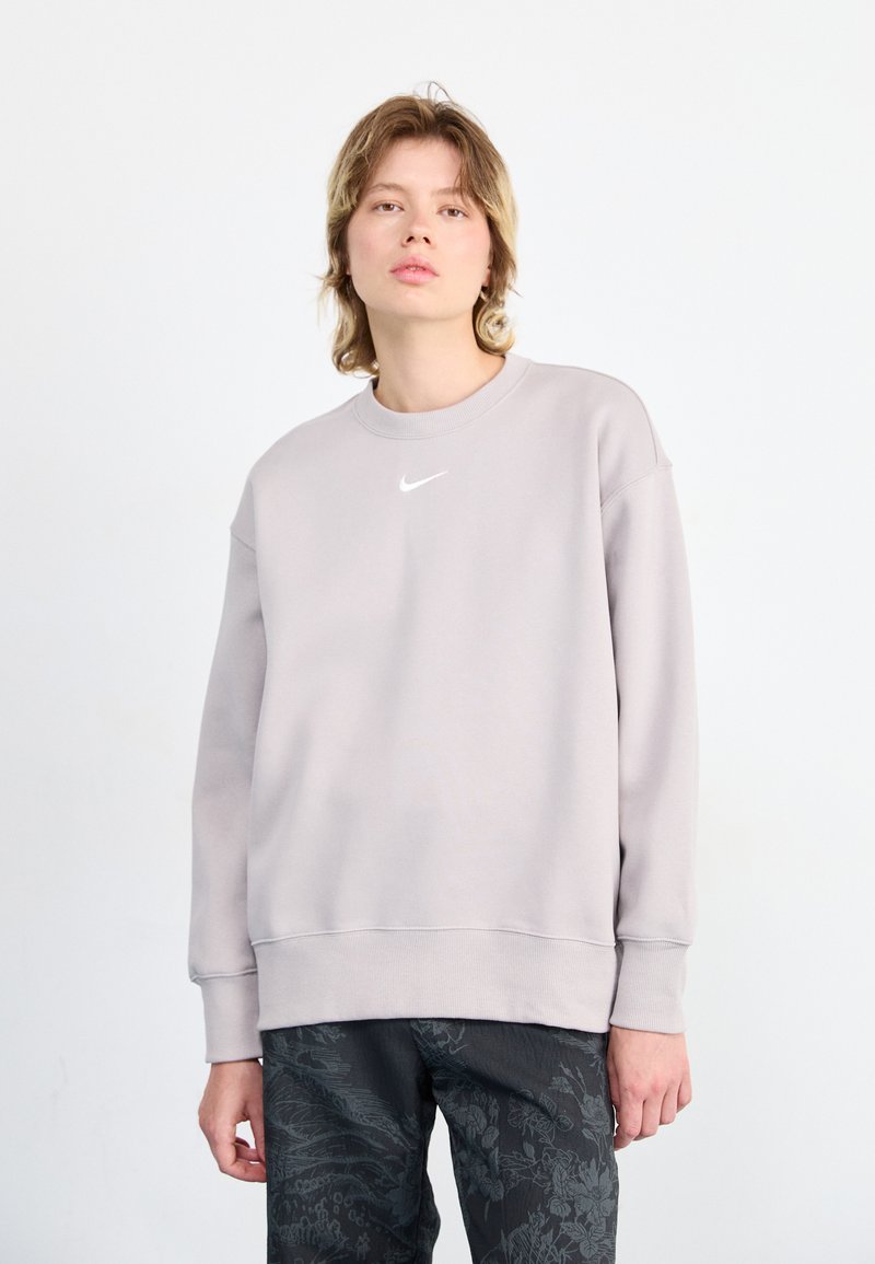 Lys grå hettegenser med rund hals og ribbestrikkede mansjetter, med en liten hvit Nike-logo på brystet. Teksturert stoff.