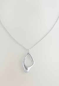 Srebrny naszyjnik z łańcuchem z abstrakcyjnym, nieregularnym otwartym wisiorkiem z gładkimi, wypolerowanymi powierzchniami na jasnym tle.