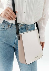 Bolso cruzado estructurado en cuero blanco y rosa claro con un acabado texturizado. Presenta una correa negra y acentos metálicos.