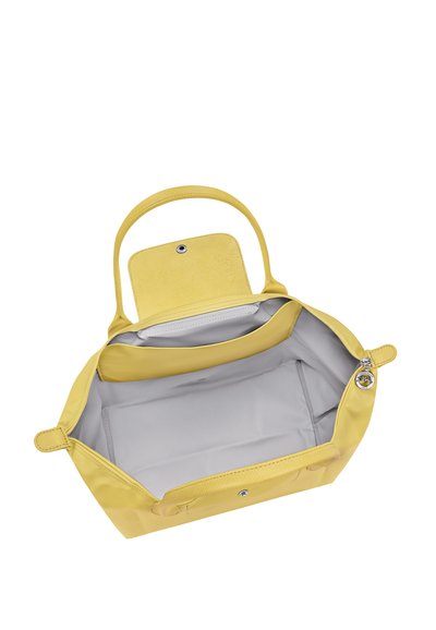 Yellow handbag with open main compartment, showing gray interior lining, a smaller internal pocket, and a snap button closure on the flap.
