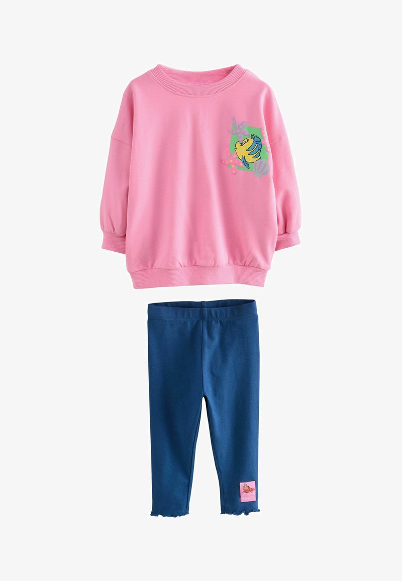 Sweat-shirt rose avec des manches bouffantes et un motif de poisson, associé à un legging bleu marine avec un ourlet festonné et une étiquette rose sur le côté.