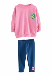 Rosa sweatshirt med puffärmar och ett fiskmotiv, tillsammans med marinblå leggings med vågig nederkant och en rosa etikett på sidan.