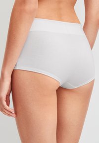 Witte katoen hipster onderbroeken met een gladde textuur, brede elastische tailleband en minimale naden, weergegeven vanuit een achterperspectief.