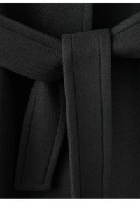 Čierny látkový opasok s hladkou textúrou, obsahujúci zložený detail a uviazaný stred, časť odevu zobrazená v detailnom záberu.