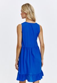 Niebieska sukienka bez rękawów z dopasowanym gorsetem i rozkloszowanym falbaniastym dołem, wykonana z lekkiego materiału. Gładka faktura, prosty design.