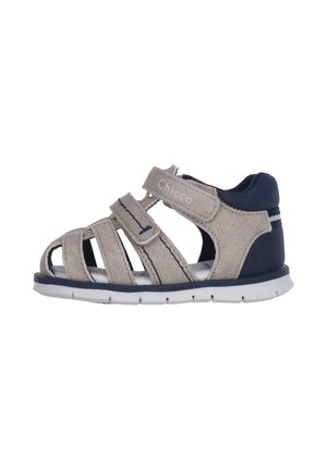 Sandalo per bambino in tessuto beige con design aperto, accenti blu navy, cinturino regolabile e suola in gomma bianca con scanalature antiscivolo.