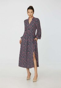 Robe à manches longues bleu marine avec motif floral rose, fermeture boutonnée à l'avant, ceinture à la taille et fente latérale. Le tissu semble léger avec une texture douce.