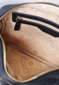 Interno di una borsa in pelle nera con zip dorata, caratterizzato da un rivestimento beige decorato con il logo "CAFÈ NOIR", comprensivo di una tasca con zip e un divisorio.