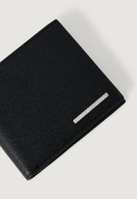 Czarny teksturowany skórzany portfel składany z małą srebrną płytką metalową z wygrawerowanym napisem "Armani Exchange" na białym tle.
