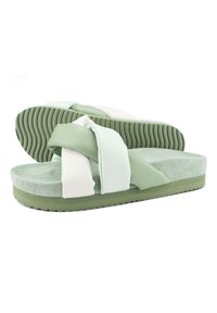 Green and white slide sandals with soft suede upper, wide straps, textured outsole, and cushioned footbed. Rounded shape, minimalistic design.