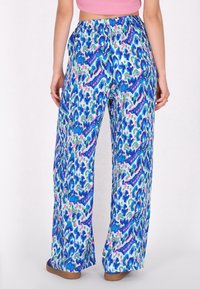 Blaue und weiße gemusterte weite Hosen mit einem lebendigen abstrakten Design in verschiedenen Blau-, Grün- und Rosatönen. Elastischer Bund.